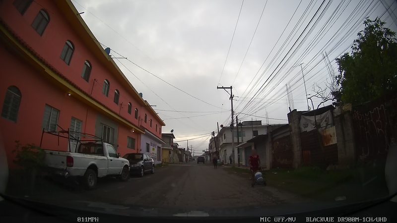 Una calle de casas de dos pisos y comercios en Tetelcingo, al norte de Cuautla, bajo un cielo nublado, Morelos