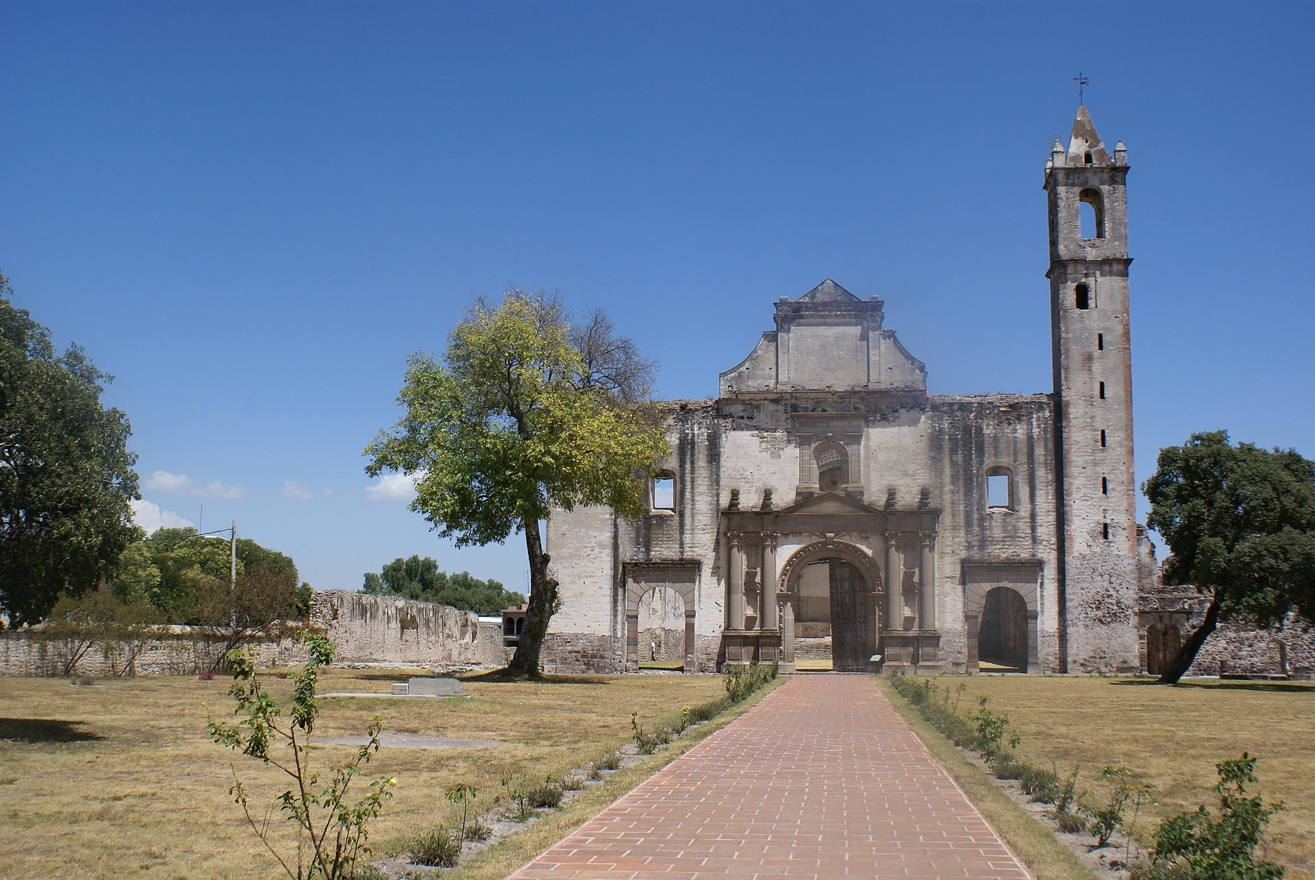 Fachada en ruinas del ex convento franciscano de Tecali de Herrera, con su campanario, al final de un andador de ladrillo, Puebla