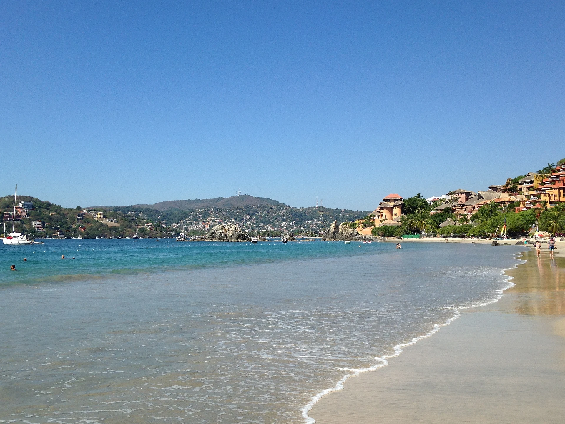 La larga curva de Playa La Ropa con los cerros y hoteles de la bahía de Zihuatanejo al fondo, Guerrero