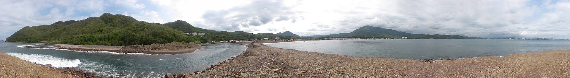 Panorámica de La Boquita: la barra de piedras en la boca de la laguna, el cerro verde y el agua tranquila de la bahía de Santiago, Colima