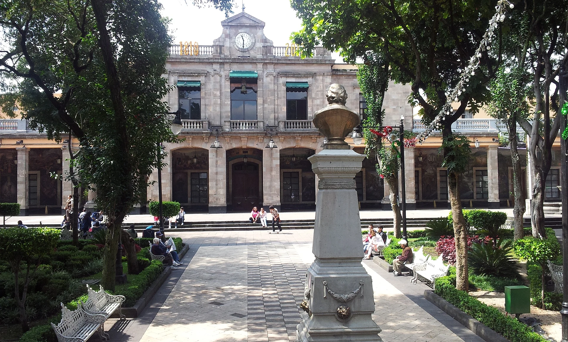 The tree-lined Jardín Principal of Tlalpan with the neoclassical municipal palace and its clock behind, Ciudad de México