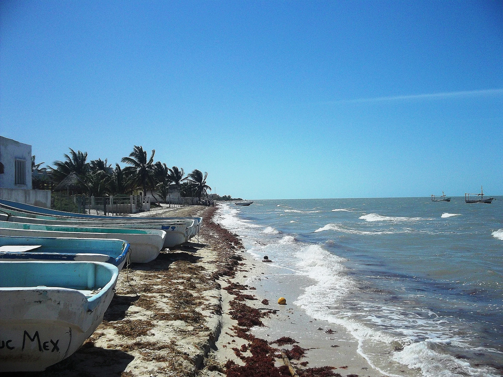 Lanchas de pesca varadas en la playa de Santa Clara, con olas rompiendo en la arena, Yucatán