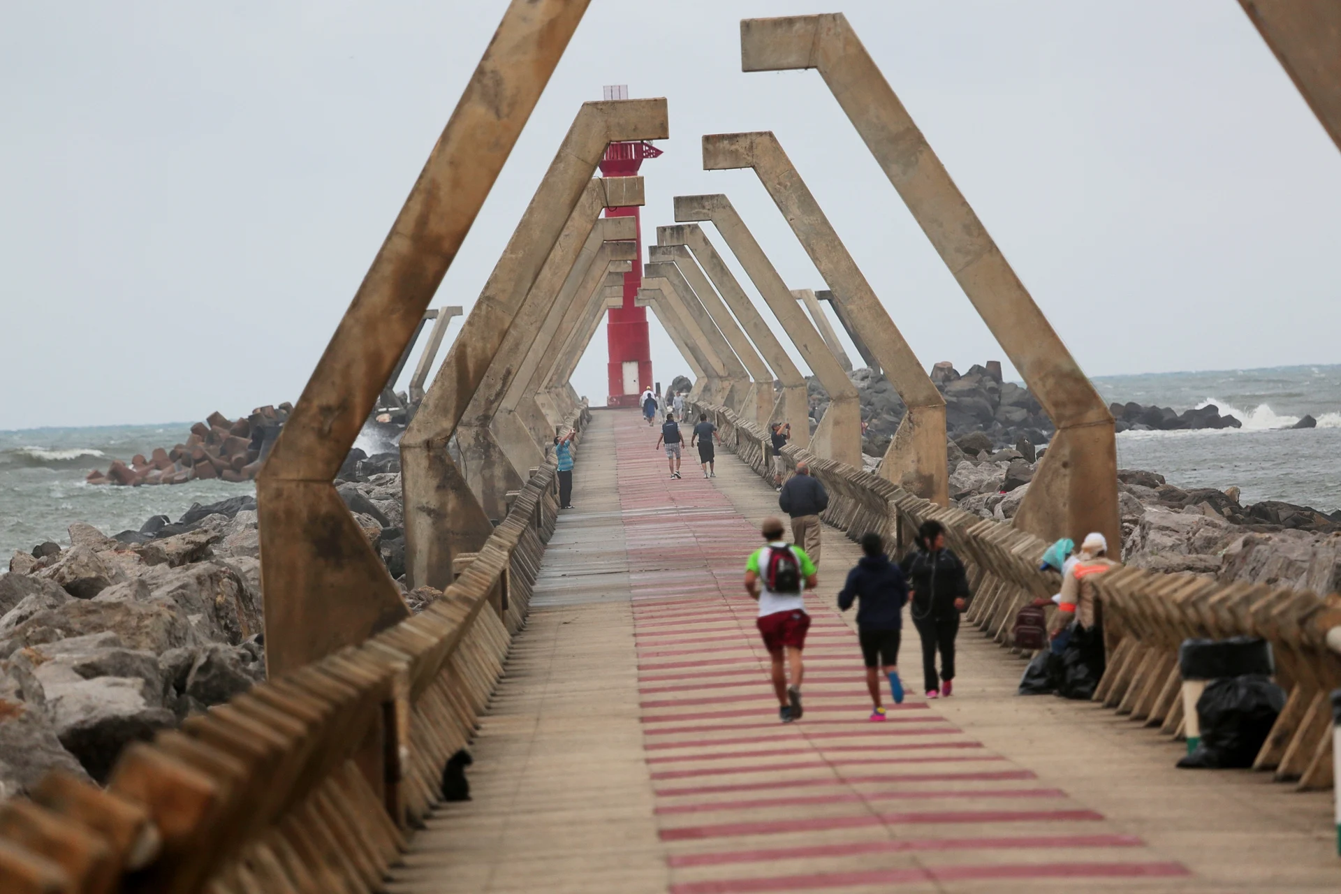 Walkers and runners on the Paseo de las Escolleras, the stone jetty at the mouth of the Coatzacoalcos River, with its red lighthouse at the end, Veracruz