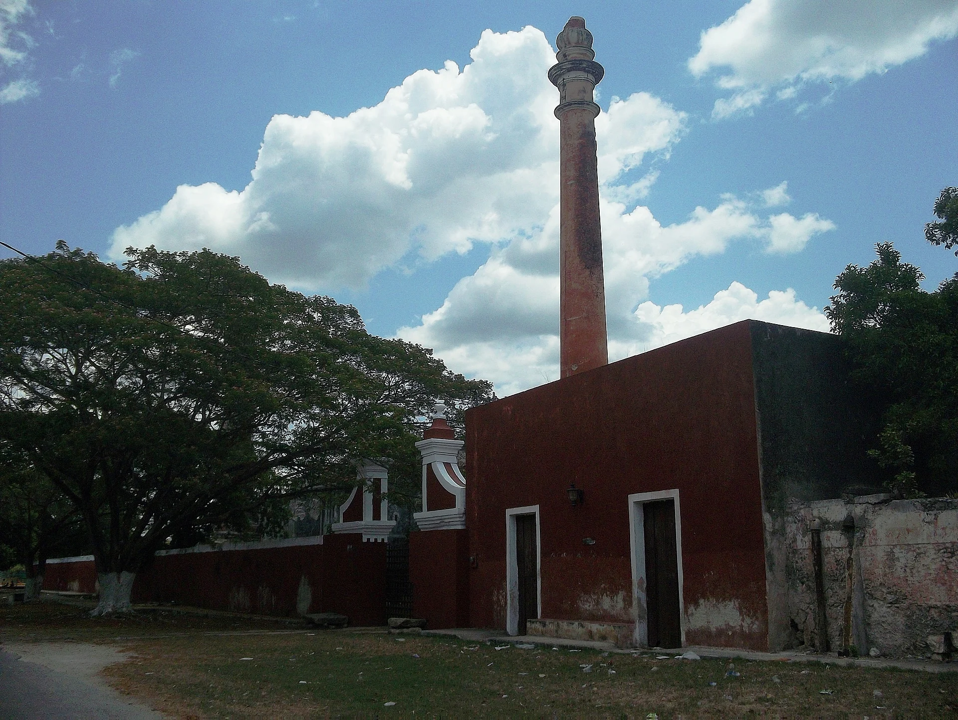 The tall brick chimney and red buildings of Hacienda San Pedro Chimay beside the road, Yucatán