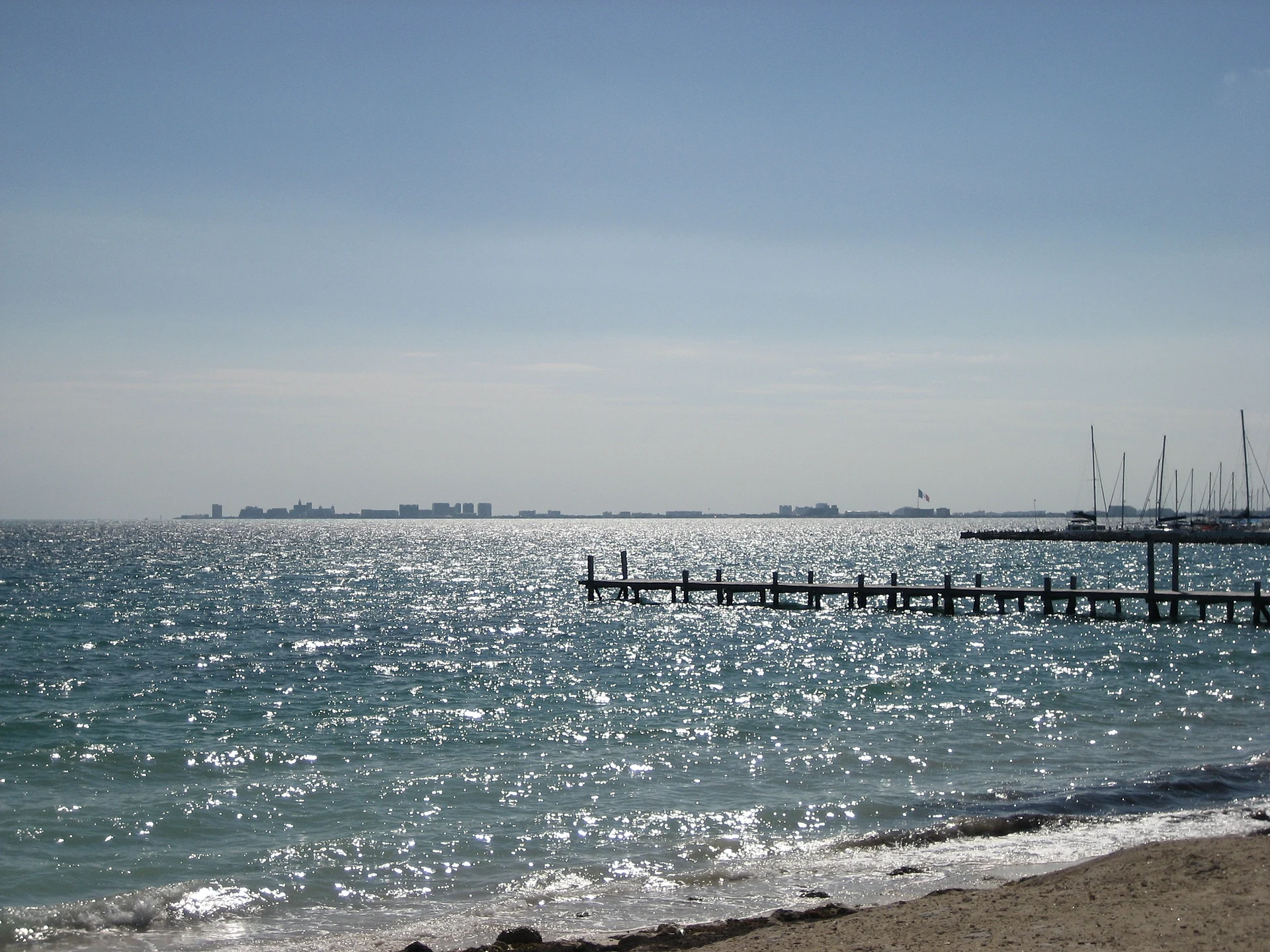 View across the water from Punta Sam toward Cancún, with a pier in the foreground, Quintana Roo