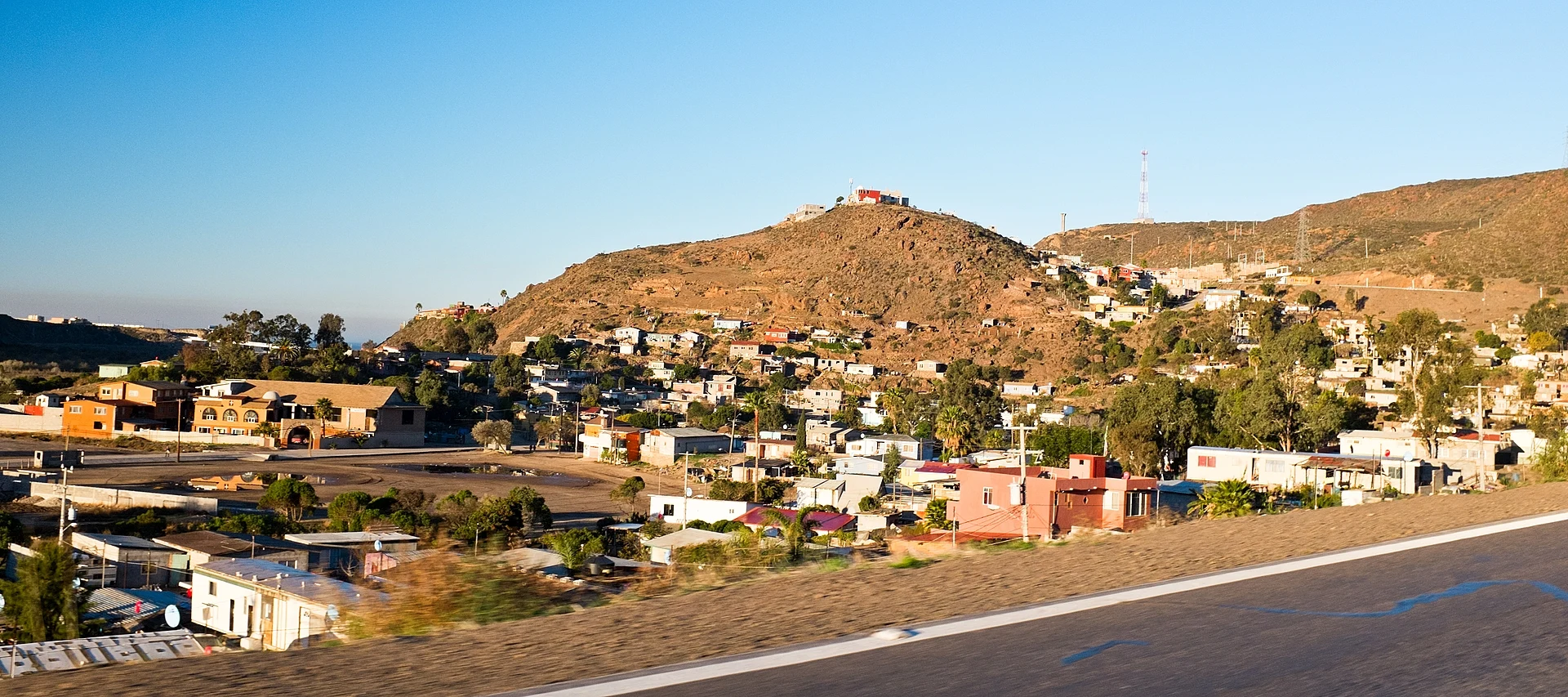 Casas de La Misión subiendo por un cerro seco sobre el valle, vistas desde la carretera federal 1, Baja California