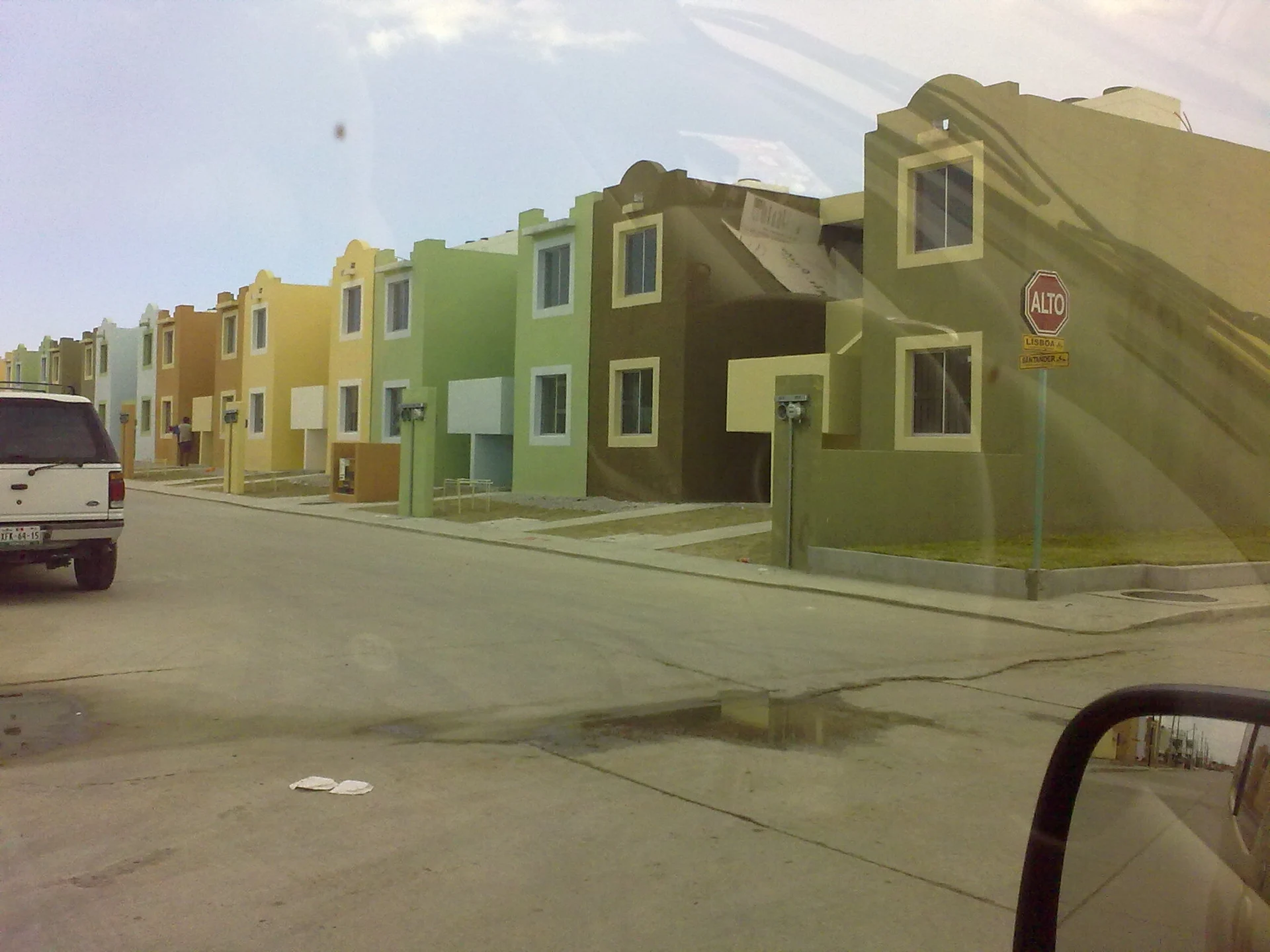A row of newly built terraced houses painted green, yellow and purple on a street in Miramar, Tamaulipas