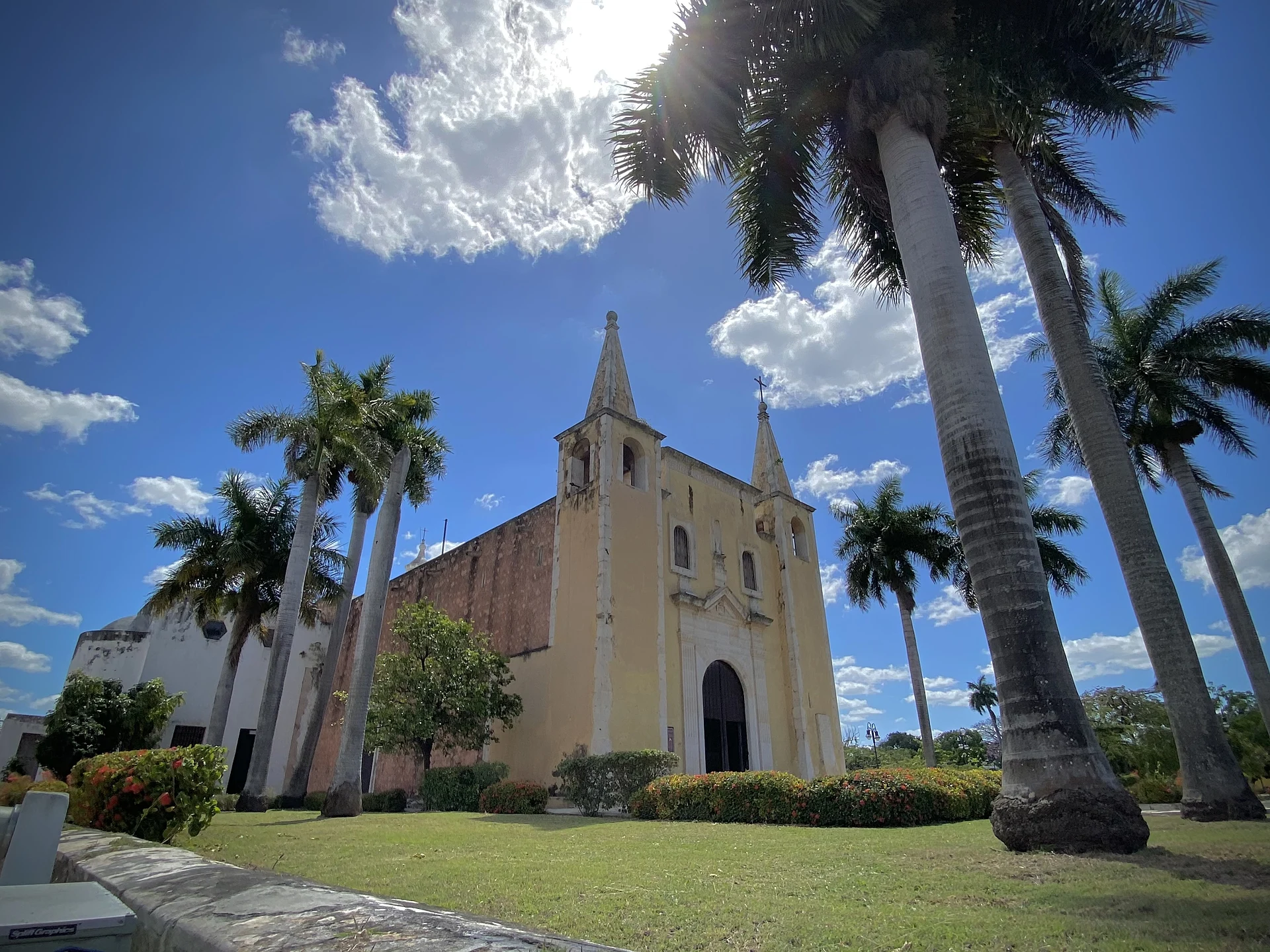 La iglesia amarilla de Santa Ana con sus dos torres en punta, entre palmeras reales, Yucatán