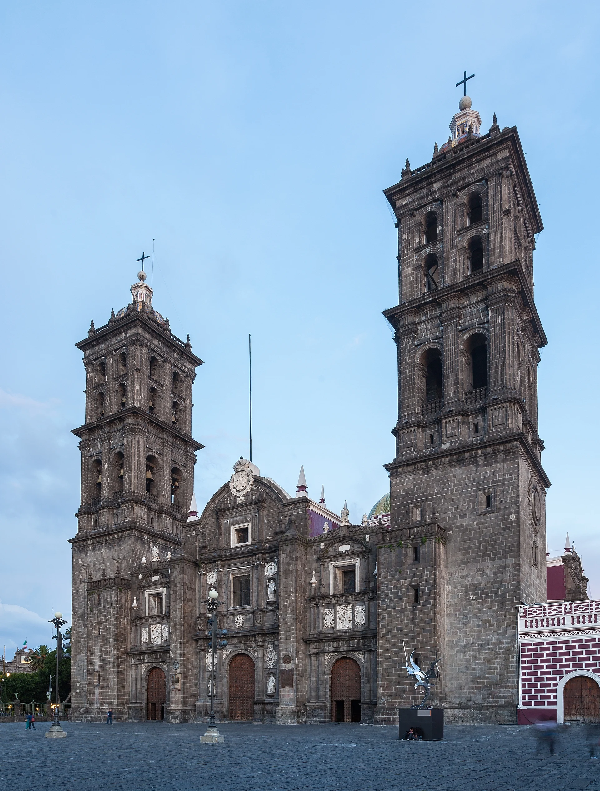 Grey stone main façade and twin bell towers of Puebla Cathedral under a blue sky