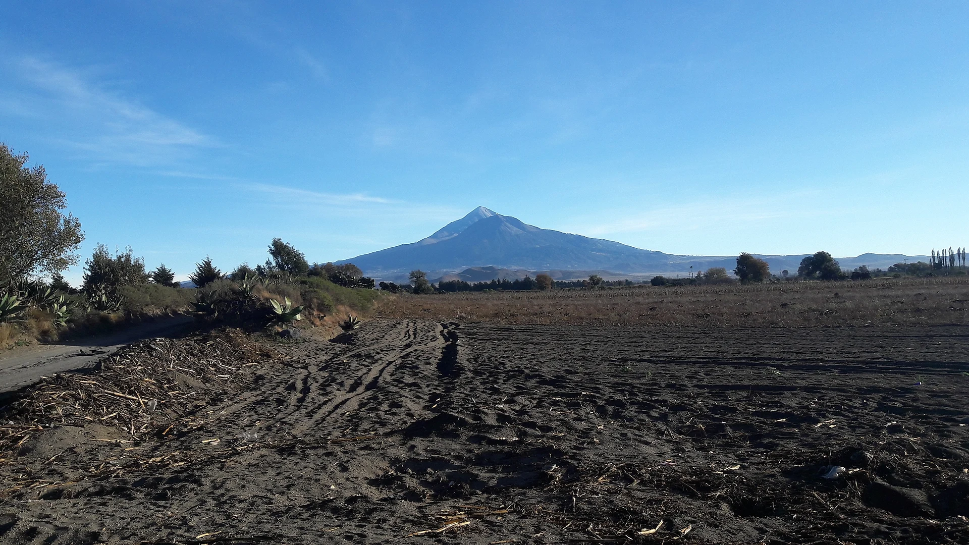 El Pico de Orizaba detrás de campos arados y magueyes en las afueras del sur de Tlachichuca, Puebla