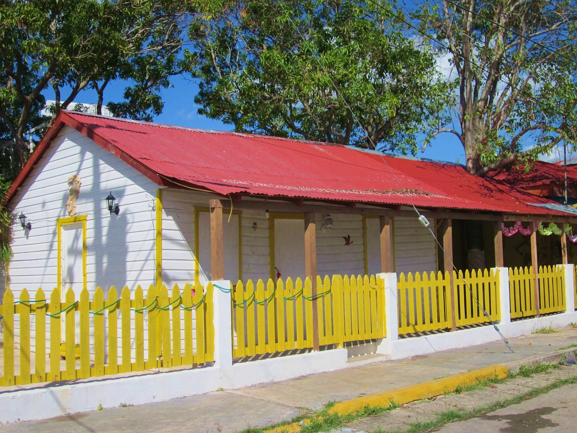 Una casa de madera blanca con techo de lámina roja y cerca amarilla en la calle 22 de Enero, en el centro de Chetumal, al estilo del antiguo Payo Obispo, Quintana Roo