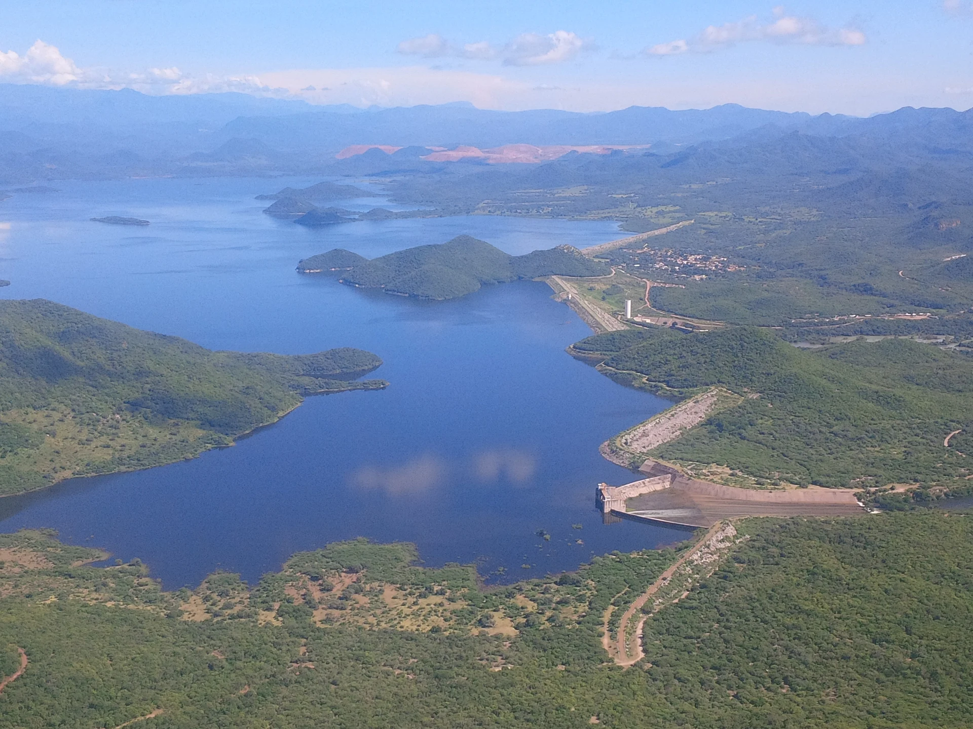 Vista aérea del embalse del Mocúzari en el río Mayo, con la cortina de tierra y el vertedor al frente y el pueblo de El Mocúzari a un lado, Presa Mocúzari, Sonora